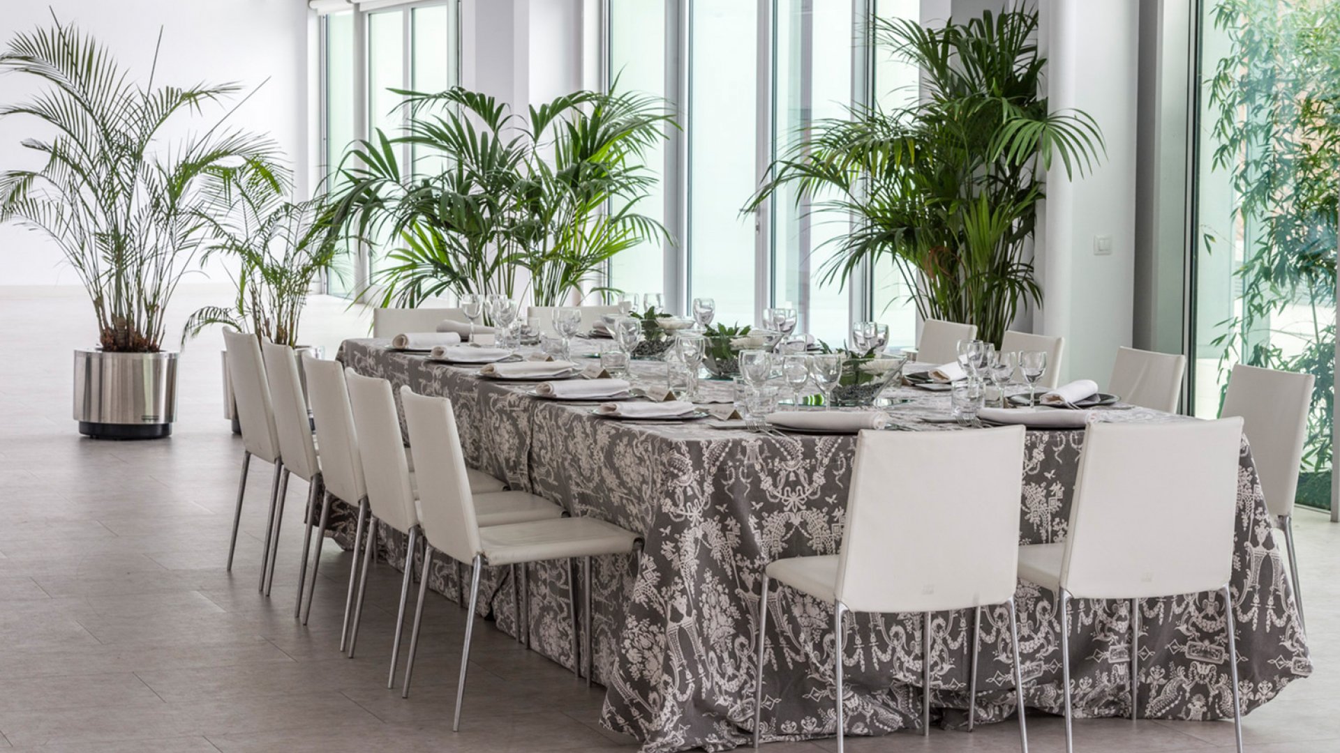 Mesa con un mantel en tonos grises y sillas blancas en el mirador del museo