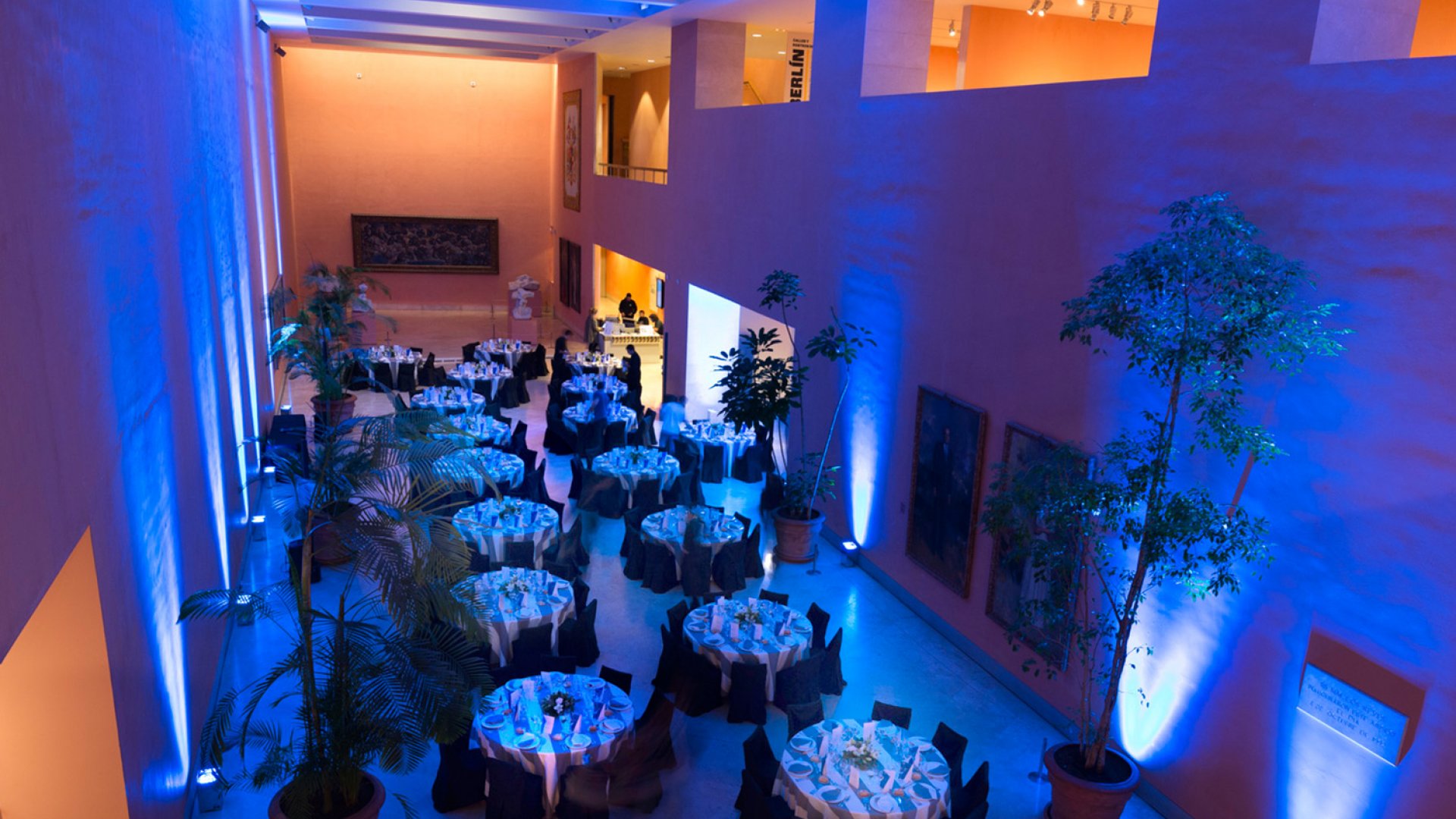 Hall central preparado con mesas para un evento ambientado con luces azuladas