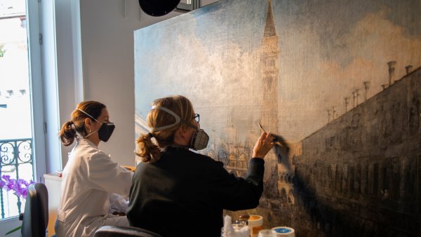 Dos empleadas del museo trabajan en el proceso de restauración de la obra La plaza de San Marcos en Venecia, de Canaletto