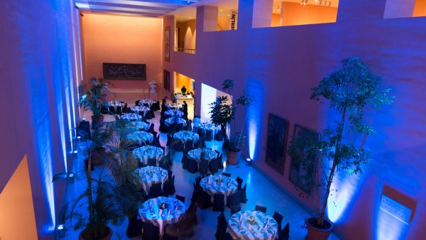 Hall central preparado con mesas para un evento ambientado con luces azuladas