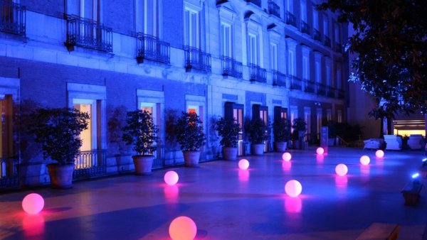 El jardín decorado con dos filas de lámparas redondas que dan luz rosa y con una luz general azulada