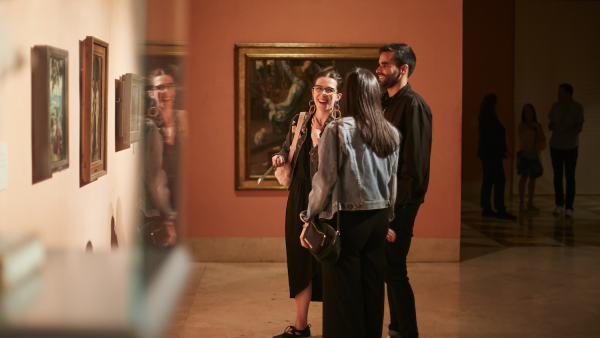 Tres personas riendo frente a uno de los cuadros del museo