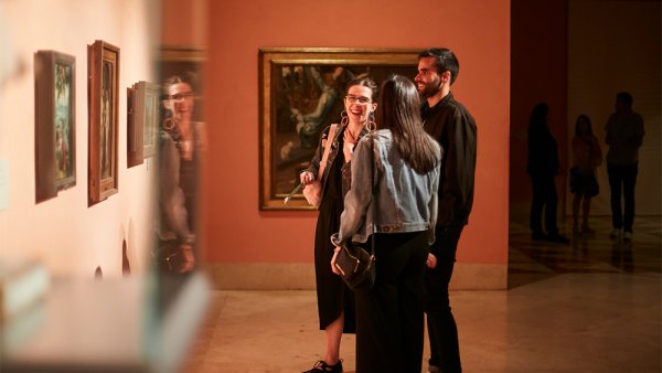 Tres personas riendo frente a uno de los cuadros del museo