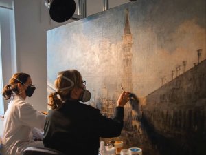 Dos restauradoras del museo trabajando en la obra "La plaza de San Marcos en Venecia" de Canaletto