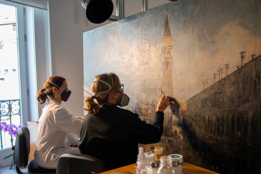 Dos empleadas del museo trabajan en el proceso de restauración de la obra La plaza de San Marcos en Venecia, de Canaletto