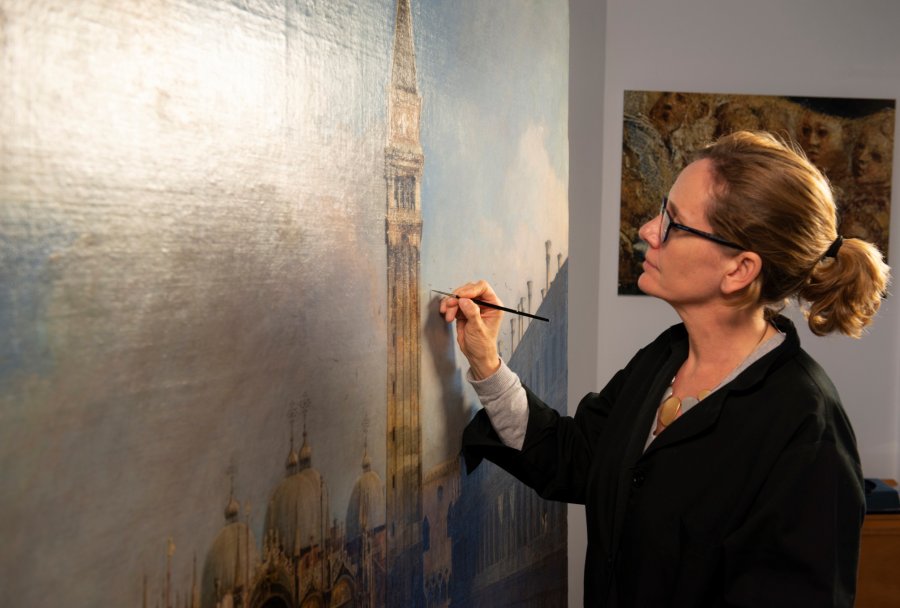 Una empleada del museo trabaja en la restauración de la obra La plaza de San Marcos en Venecia, de Canaletto