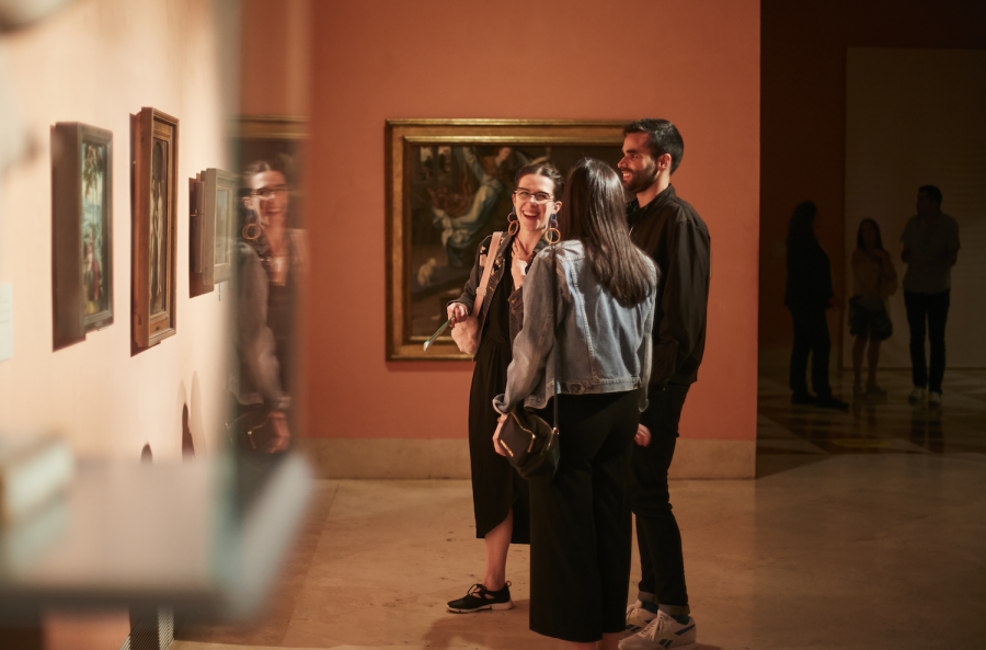 Tres personas riendo frente a uno de los cuadros del museo