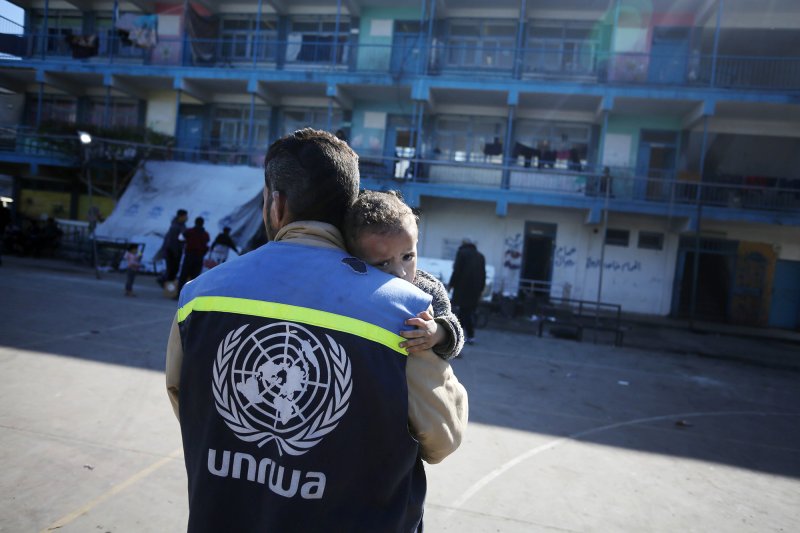 Un trabajador humanitario de UNRWA carga a un niño herido en el patio de una escuela convertida en refugio en el centro de Gaza, uno de los hasta 150 refugios de emergencia gestionados por UNRWA, enero de 2024. 