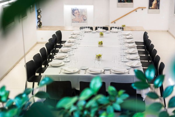 En medio de la sala hay una mesa rectangular muy grande en la que está preparada para una comida con muchos comensales